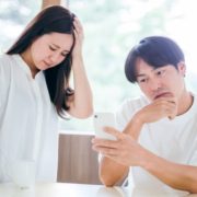 スマートフォンを見て悩む男女