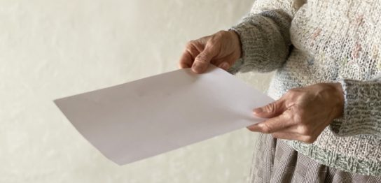 用紙を持つ高齢者の手元