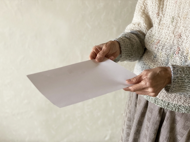 用紙を持つ高齢者の手元